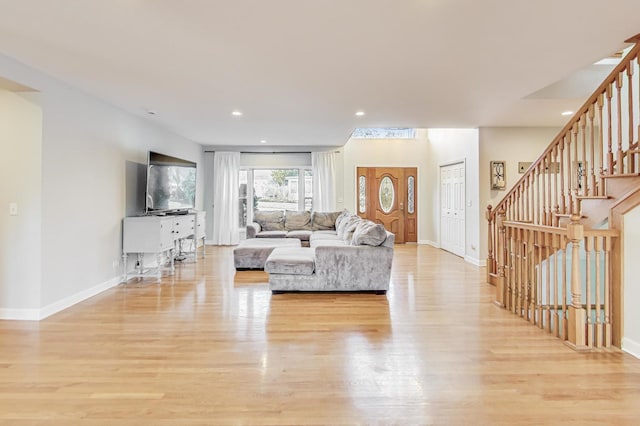 unfurnished living room with light wood-style flooring, stairway, baseboards, and recessed lighting