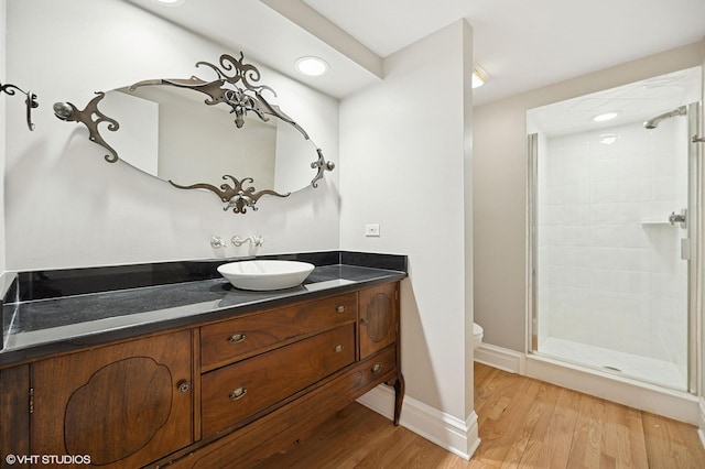 full bathroom featuring baseboards, toilet, wood finished floors, vanity, and a shower stall