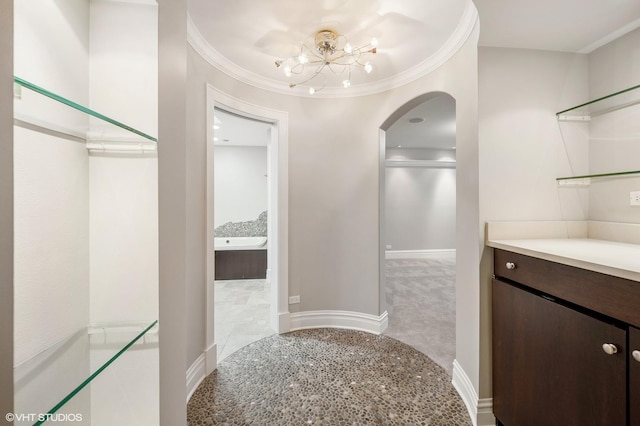 hall featuring a chandelier, ornamental molding, carpet flooring, and baseboards