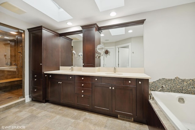 bathroom with a bath, double vanity, visible vents, and a sink