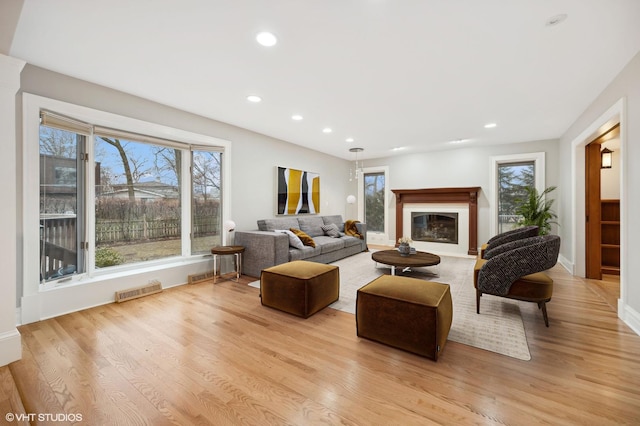 living room with a wealth of natural light, light wood-type flooring, visible vents, and recessed lighting