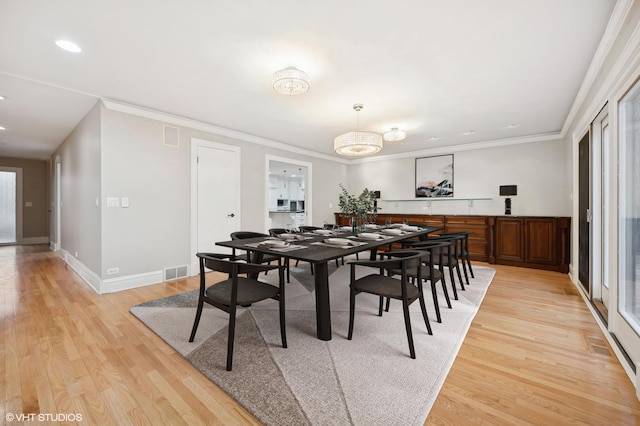 dining area with light wood-type flooring, baseboards, visible vents, and crown molding