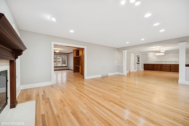 unfurnished living room with recessed lighting, ornate columns, a fireplace with flush hearth, light wood-type flooring, and baseboards