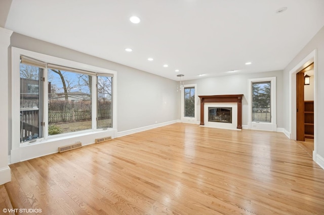 unfurnished living room featuring recessed lighting, a glass covered fireplace, visible vents, and light wood-style floors