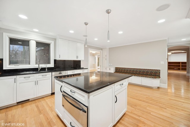 kitchen featuring arched walkways, white cabinets, a sink, and a warming drawer