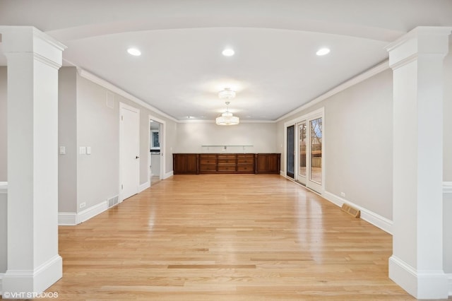 unfurnished room with visible vents, decorative columns, and light wood finished floors