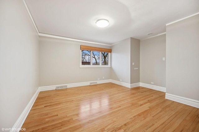 unfurnished room featuring baseboards, ornamental molding, visible vents, and light wood-style floors