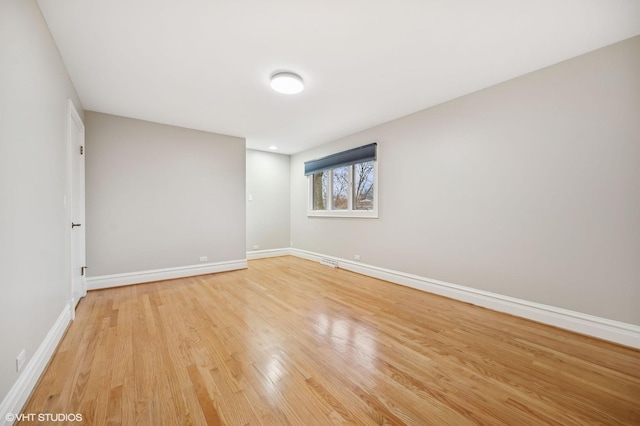 empty room with light wood-style floors, visible vents, and baseboards