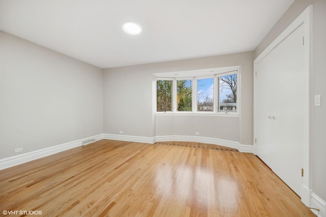 unfurnished room featuring visible vents, light wood-style flooring, and baseboards