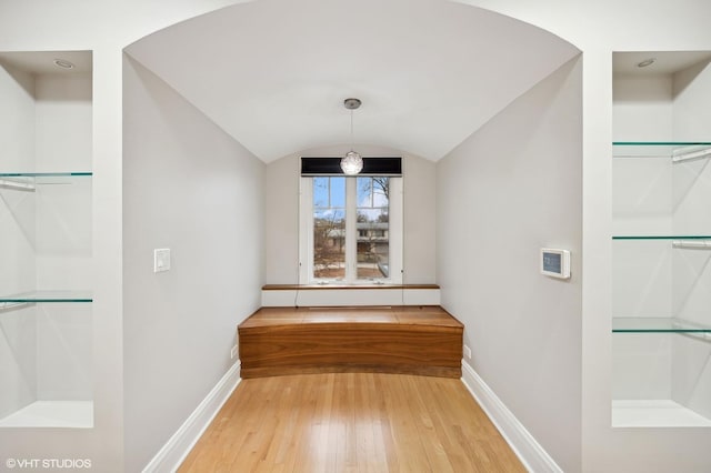 unfurnished dining area featuring lofted ceiling, wood-type flooring, and baseboards