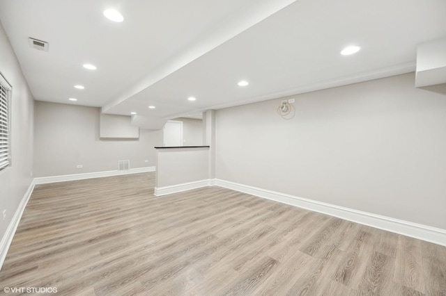 finished below grade area with light wood-style floors, recessed lighting, visible vents, and baseboards