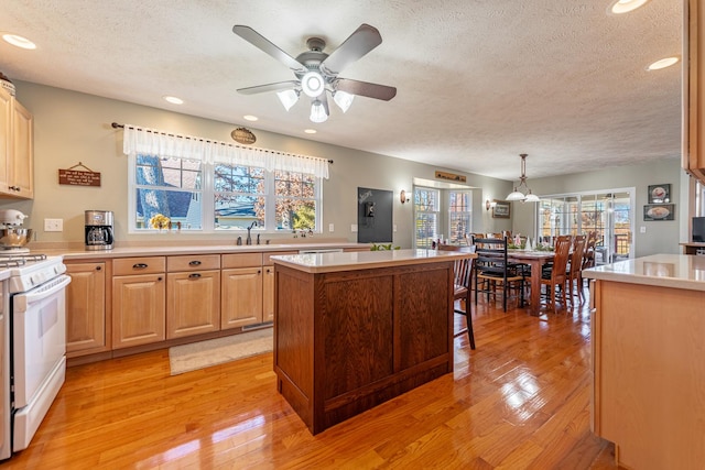 kitchen featuring white gas stove, light countertops, and light wood-style flooring