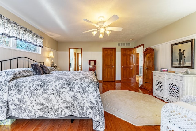 bedroom with a ceiling fan, visible vents, and wood finished floors