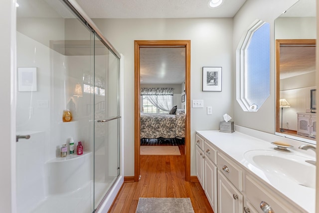 ensuite bathroom featuring wood finished floors, a stall shower, connected bathroom, and vanity