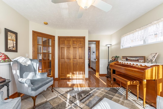 living area featuring ceiling fan, a textured ceiling, and wood finished floors