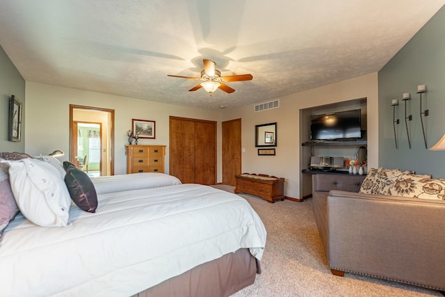 bedroom with baseboards, visible vents, a ceiling fan, light colored carpet, and a textured ceiling