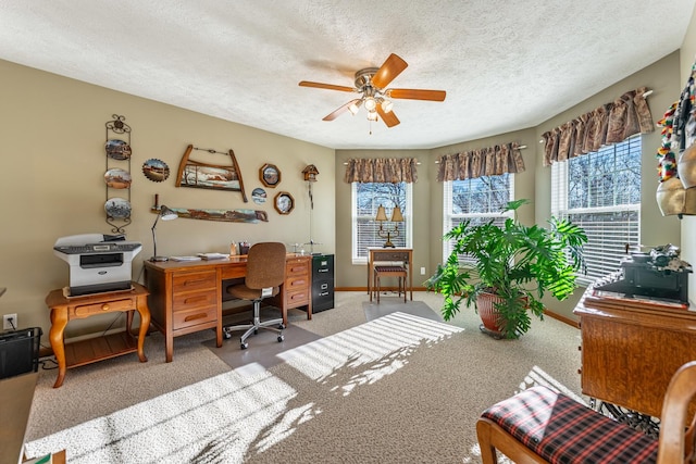 carpeted home office with a ceiling fan, a textured ceiling, and baseboards