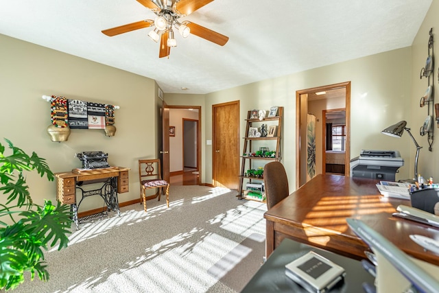 carpeted office space with ceiling fan and baseboards