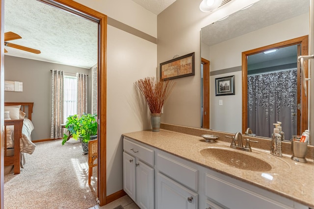 bathroom with a ceiling fan, baseboards, a textured ceiling, and vanity