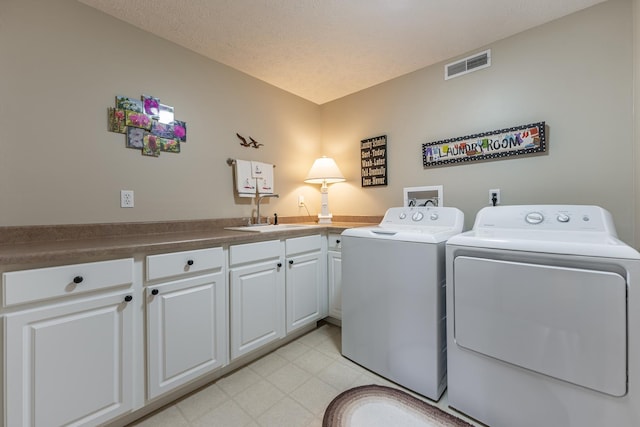 clothes washing area featuring a sink, visible vents, cabinet space, light floors, and washer and clothes dryer