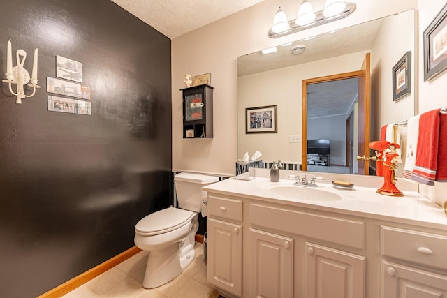 bathroom with toilet, vanity, a textured ceiling, tile patterned flooring, and baseboards