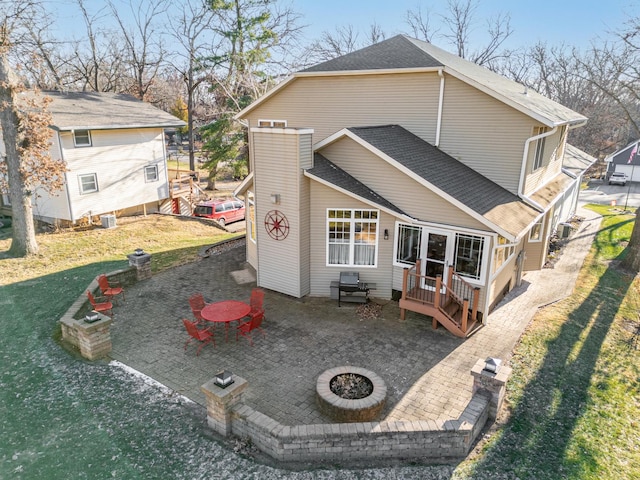 rear view of house featuring an outdoor fire pit, a lawn, a patio, roof with shingles, and central AC