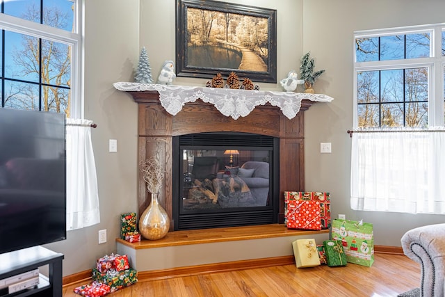 interior details with baseboards, wood finished floors, and a glass covered fireplace