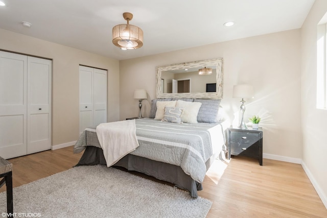 bedroom featuring recessed lighting, baseboards, two closets, and wood finished floors