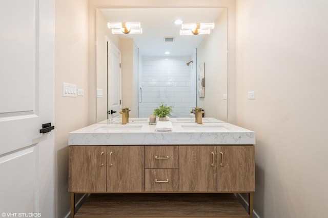 full bath with double vanity, wood finished floors, a sink, and visible vents