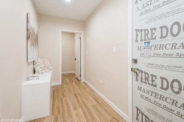 hall featuring light wood-type flooring and baseboards