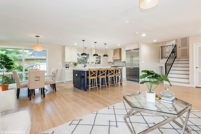 living area featuring stairway, recessed lighting, light wood-style flooring, and baseboards