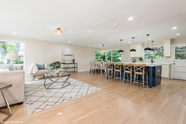 living area with baseboards, plenty of natural light, light wood-style flooring, and recessed lighting