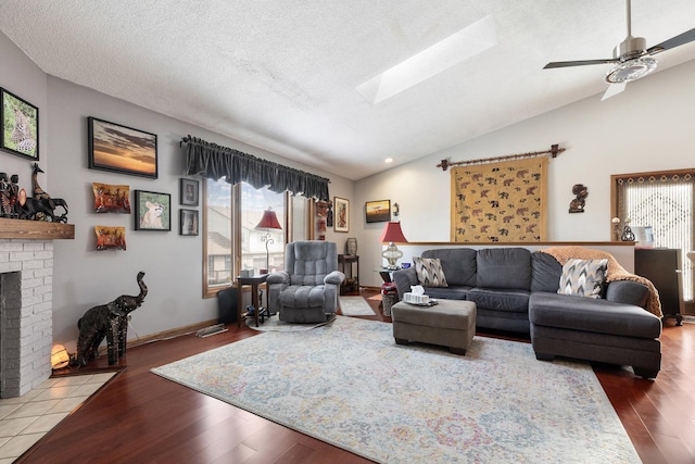 living room featuring lofted ceiling with skylight, a fireplace, and wood finished floors