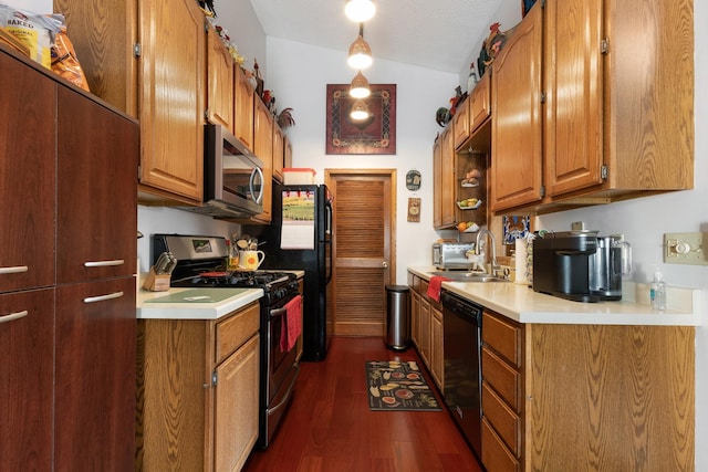 kitchen with stainless steel appliances, a sink, light countertops, brown cabinets, and dark wood finished floors