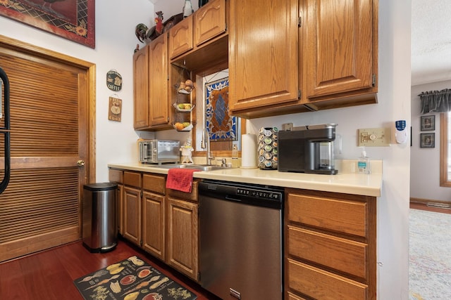 kitchen with light countertops, stainless steel dishwasher, a sink, and dark wood finished floors