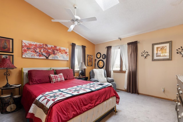 bedroom with light colored carpet, lofted ceiling with skylight, ceiling fan, a textured ceiling, and baseboards