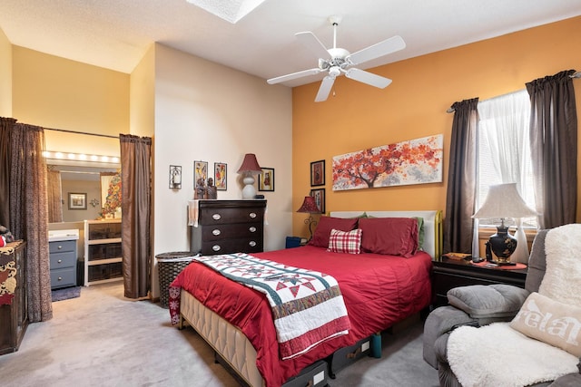 bedroom featuring a high ceiling, connected bathroom, a ceiling fan, and light colored carpet