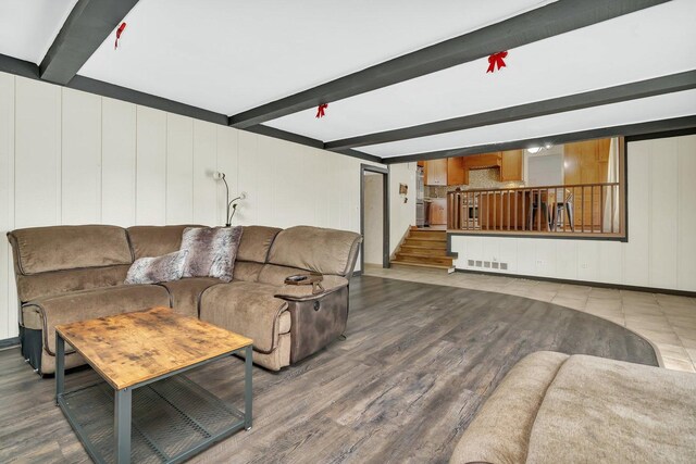 living room with wood finished floors, visible vents, beam ceiling, and stairs