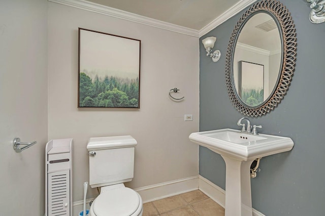 bathroom with baseboards, toilet, tile patterned floors, crown molding, and a sink