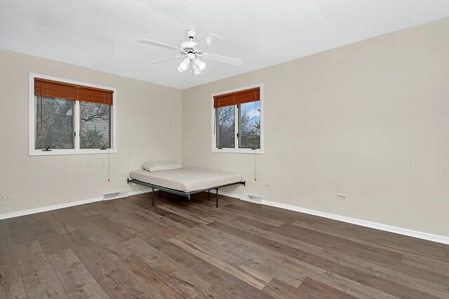 unfurnished room with a ceiling fan, wood finished floors, visible vents, and baseboards