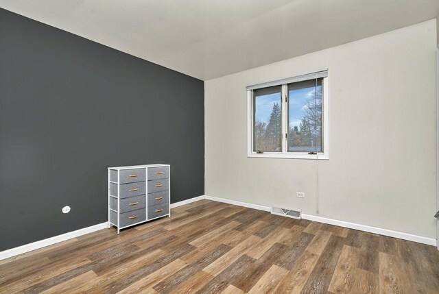 unfurnished room with visible vents, baseboards, and wood finished floors