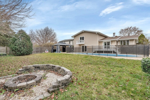 back of property featuring a fenced in pool, a yard, a gazebo, an outdoor fire pit, and a fenced backyard