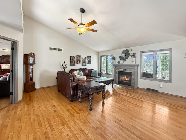 living area featuring visible vents, a fireplace, light wood-style flooring, and ceiling fan