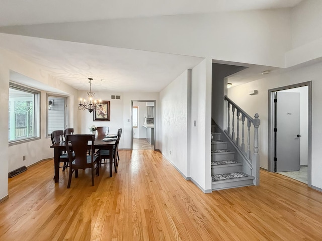 dining room featuring light wood-style floors, visible vents, a notable chandelier, and stairs