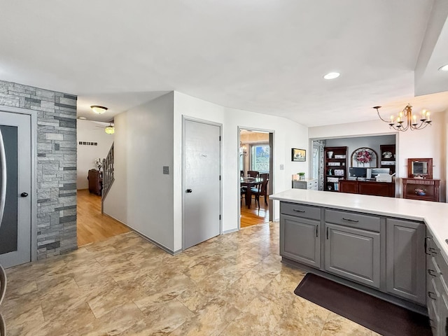 kitchen featuring gray cabinetry, ceiling fan with notable chandelier, a peninsula, visible vents, and light countertops