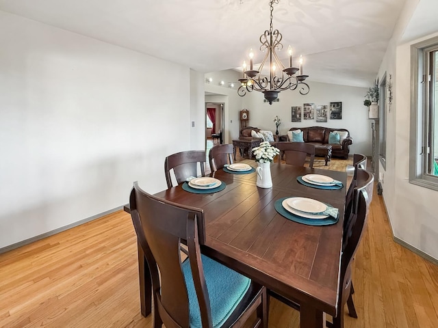 dining area with light wood-style floors, lofted ceiling, baseboards, and an inviting chandelier