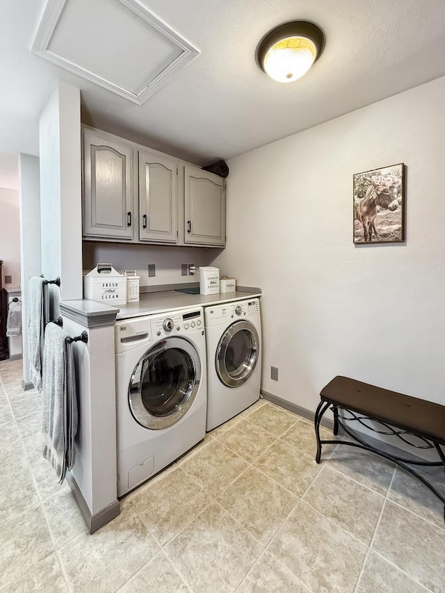 washroom featuring cabinet space, attic access, light tile patterned floors, baseboards, and washer and clothes dryer