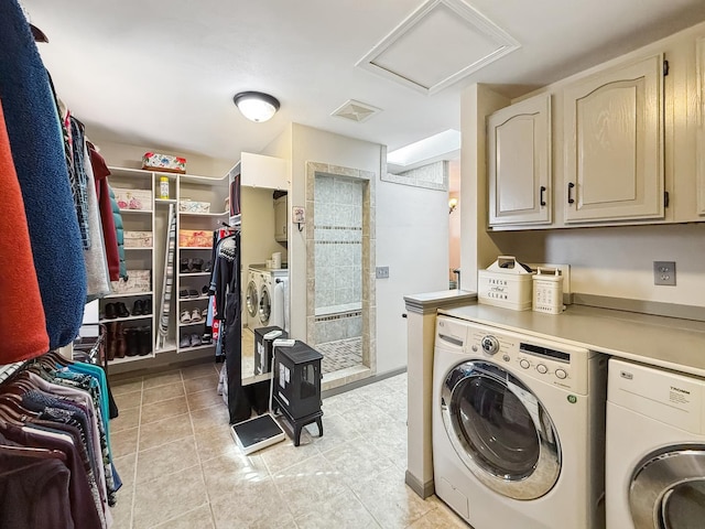 laundry room with cabinet space, attic access, washer and clothes dryer, and light tile patterned flooring