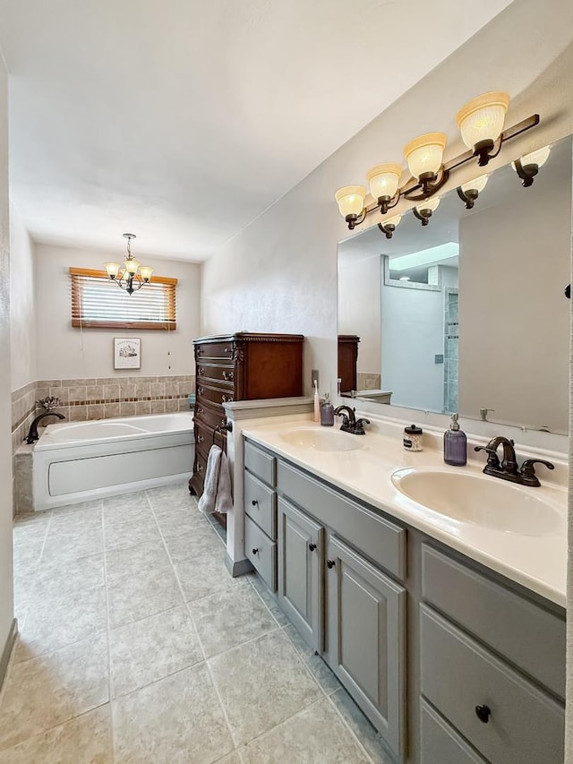 bathroom with a garden tub, double vanity, a sink, and a chandelier