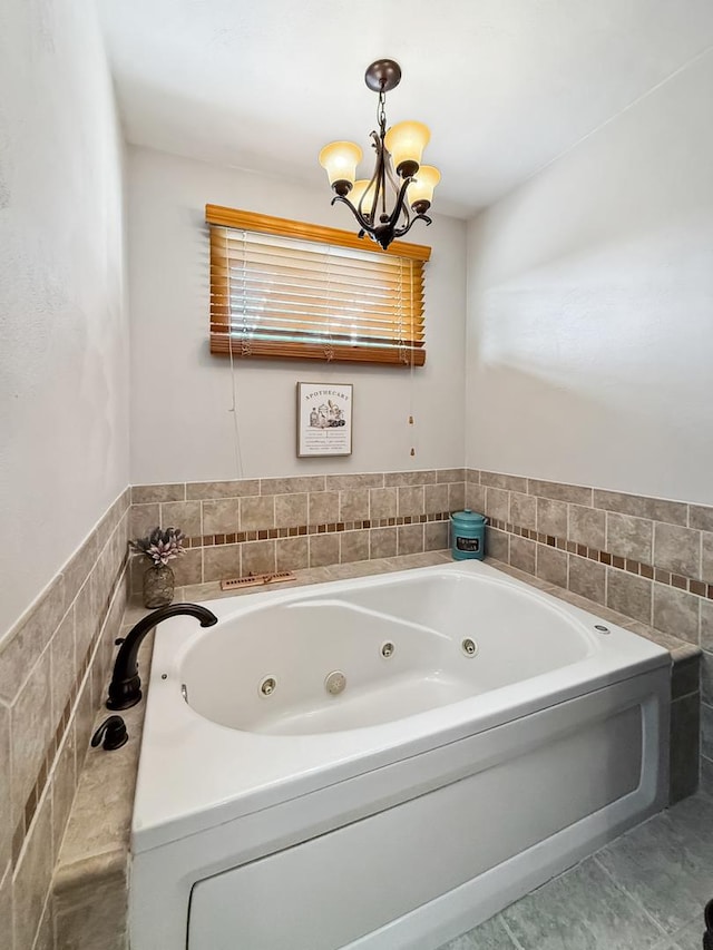 bathroom featuring a jetted tub and a notable chandelier